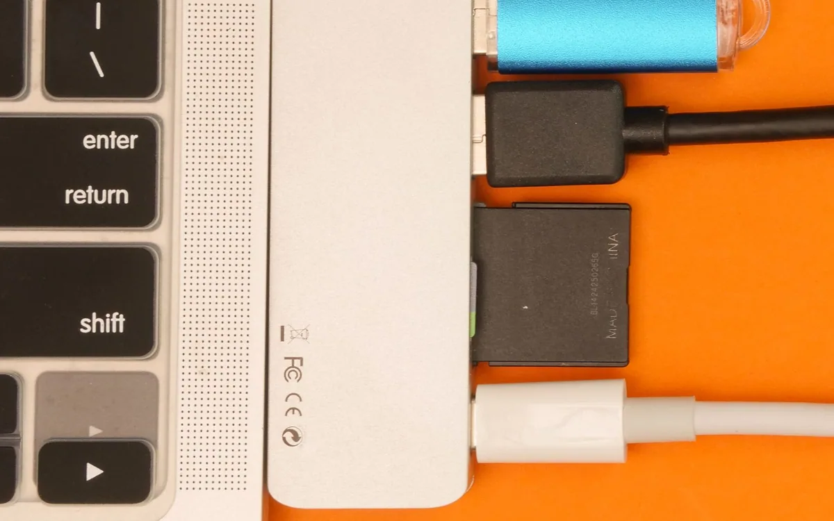 A USB hub with several connected cables is attached to a laptop.